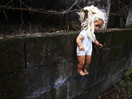 Old toy doll hanging on a fenceの写真素材