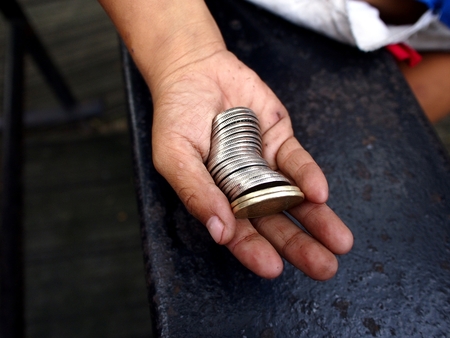 Hand of a boy holding a bunch of coinsの写真素材