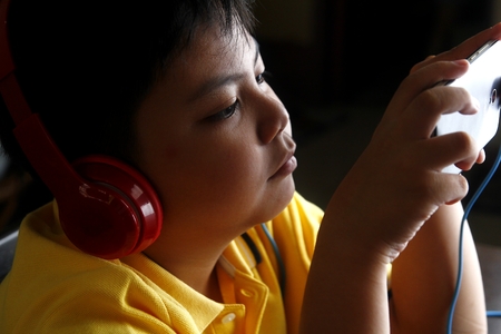 Young Asian boy with a smartphone and headphonesの写真素材