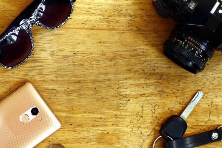 Photo of a manual camera, car key and sunglasses on a table inside a bedroomの写真素材