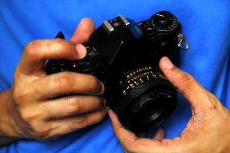 Close up photo of a pair of a manâs hands holding a 35mm manual film cameraの写真素材