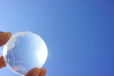 Globe on child hand against blue sky の写真素材