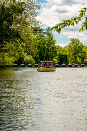 Scenic Boat Ride on the River Avon Surrounded by Lush Greenery and Tranquil Waters Under a Cloudy Blue Skyの写真素材