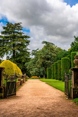 Majestic Garden Path with Ornamental Gates and Lush Topiary in the English Countrysideの写真素材
