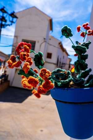 Colorful Crochet Flowers in a Blue Pot with a Quaint Andalusian Village Backdropの写真素材