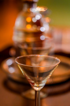 Selective focus on a crystal martini glass rim with a gleaming decanter softly blurred behindの写真素材