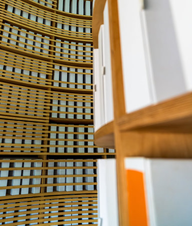 Close-up of white archival binders neatly aligned on circular birch-plywood shelves against a curved...