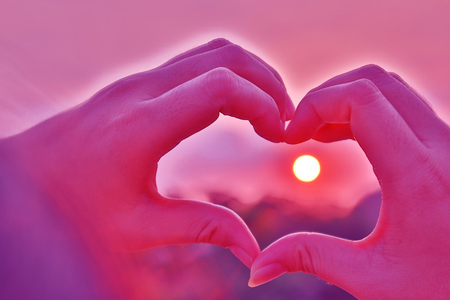 Hand in heart shape on the valley and sunset background.の写真素材