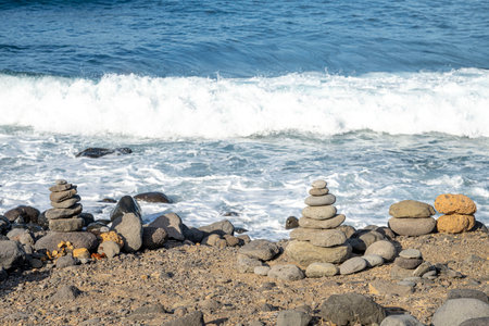 Pyramid of stones on the seashore against the background of the wavesの写真素材