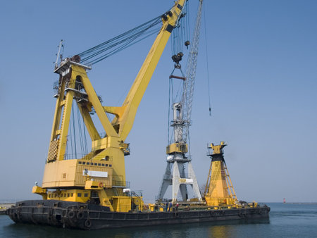 Swimming crane transporting another crane to a dock