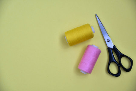 scissors and thread on yellow background