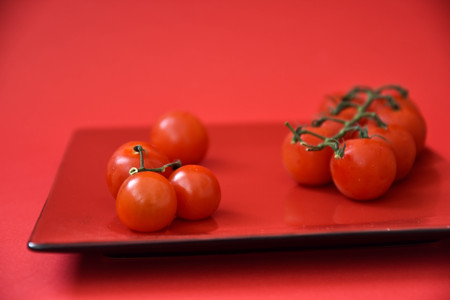 Cherry tomatoes on a red plate.の写真素材