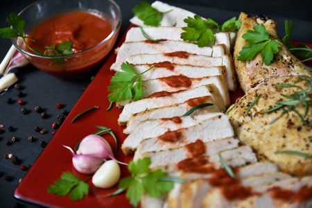 Pork steak with sauce and garlic on a red plate.の写真素材