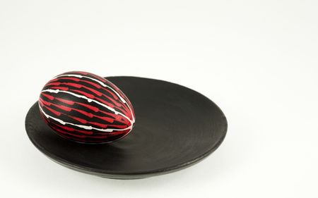 Hand colored egg on a black plate over the white backgroundの写真素材