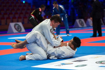 ABU DHABI, UAE - APRIL 19, 2016: ABU DHABI WORLD PROFESSIONAL JIU-JITSU CHAMPIONSHIP 2016 in the IPIC ARENA. Fighters with white belts fight on the mat.のeditorial素材