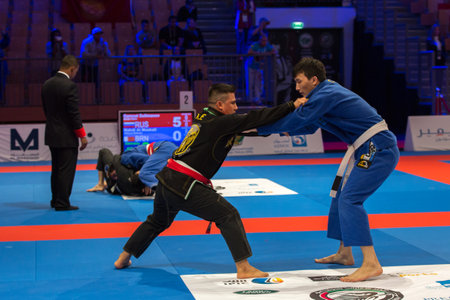 ABU DHABI, UAE - APRIL 19, 2016: ABU DHABI WORLD PROFESSIONAL JIU-JITSU CHAMPIONSHIP 2016 in the IPIC ARENA. Fighters with white belts fighting on the mat.のeditorial素材