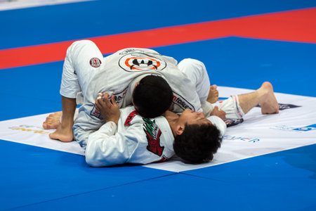 ABU DHABI, UAE - APRIL 19, 2016: ABU DHABI WORLD PROFESSIONAL JIU-JITSU CHAMPIONSHIP 2016 in the IPIC ARENA. Men in white kimonos fighting in the parterre.のeditorial素材