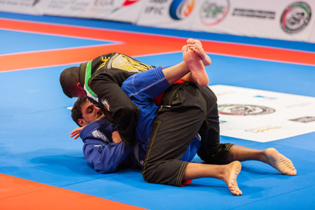 ABU DHABI, UAE - APRIL 19, 2016: ABU DHABI WORLD PROFESSIONAL JIU-JITSU CHAMPIONSHIP 2016 in the IPIC ARENA. Fighters in the black and blue kimono are fighting on the mat.のeditorial素材