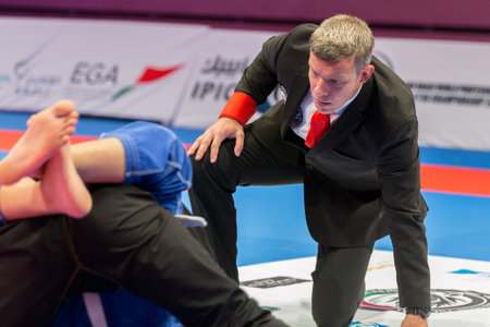 ABU DHABI, UAE - APRIL 19, 2016: ABU DHABI WORLD PROFESSIONAL JIU-JITSU CHAMPIONSHIP 2016 in the IPIC ARENA. Close view of referee following fighters fighting in the parterre.のeditorial素材