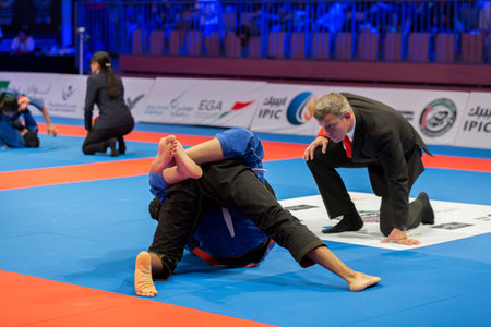 ABU DHABI, UAE - APRIL 19, 2016: ABU DHABI WORLD PROFESSIONAL JIU-JITSU CHAMPIONSHIP 2016 in the IPIC ARENA. Referee following fighters fighting in the parterre.のeditorial素材