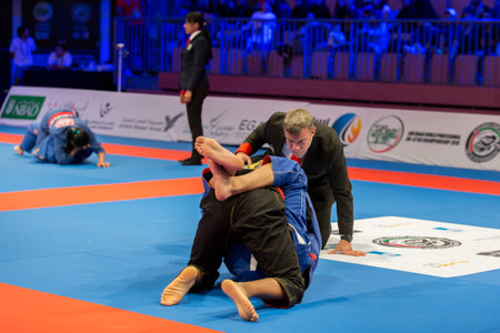 ABU DHABI, UAE - APRIL 19, 2016: ABU DHABI WORLD PROFESSIONAL JIU-JITSU CHAMPIONSHIP 2016 in the IPIC ARENA. Referee following fighters fighting in the parterre.のeditorial素材
