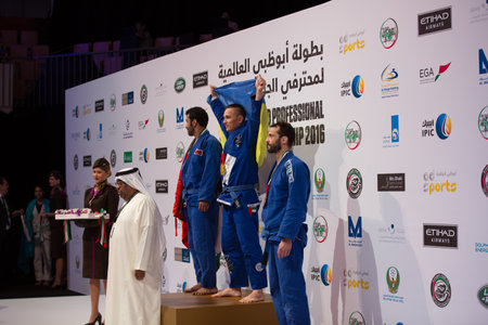 ABU DHABI, UAE - APRIL 19, 2016: ABU DHABI WORLD PROFESSIONAL JIU-JITSU CHAMPIONSHIP 2016 in the IPIC ARENA. Winners on the podium. Fighter holds  Ukrainian flag.のeditorial素材