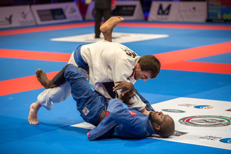 ABU DHABI, UAE - APRIL 19, 2016: ABU DHABI WORLD PROFESSIONAL JIU-JITSU CHAMPIONSHIP 2016 in the IPIC ARENA. Fighters in the white and blue kimonos fight in parterre.のeditorial素材
