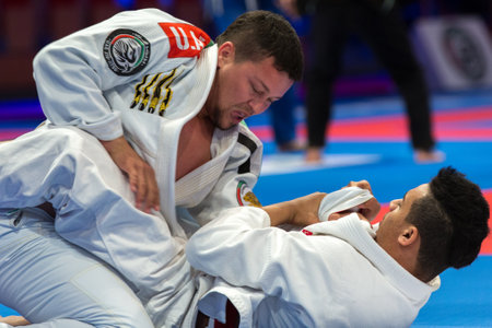 ABU DHABI, UAE - APRIL 19, 2016: ABU DHABI WORLD PROFESSIONAL JIU-JITSU CHAMPIONSHIP 2016 in the IPIC ARENA. Fighters in white kimonos fighting on the mat.のeditorial素材