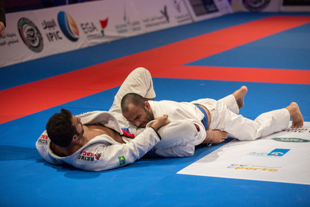 ABU DHABI, UAE - APRIL 19, 2016: ABU DHABI WORLD PROFESSIONAL JIU-JITSU CHAMPIONSHIP 2016 in the IPIC ARENA. Two fighters in the white kimonos fight in parterre.のeditorial素材