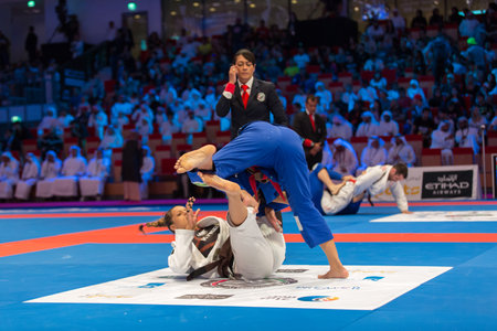 ABU DHABI, UAE - APRIL 19, 2016: ABU DHABI WORLD PROFESSIONAL JIU-JITSU CHAMPIONSHIP 2016 in the IPIC ARENA. Female fighters on the mat. Judge next to them.のeditorial素材
