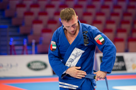 ABU DHABI, UAE - APRIL 19, 2016: ABU DHABI WORLD PROFESSIONAL JIU-JITSU CHAMPIONSHIP 2016 in the IPIC ARENA. Fighter with blue belt adjusts his kimono.のeditorial素材