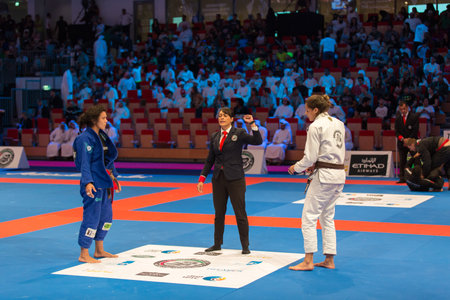 ABU DHABI, UAE - APRIL 19, 2016: ABU DHABI WORLD PROFESSIONAL JIU-JITSU CHAMPIONSHIP 2016 in the IPIC ARENA. Female fighters on the mat. Judge announces fighting.のeditorial素材