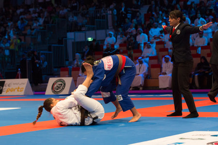ABU DHABI, UAE - APRIL 19, 2016: ABU DHABI WORLD PROFESSIONAL JIU-JITSU CHAMPIONSHIP 2016 in the IPIC ARENA. Female fighters in the parterre. Referre stops fighting.のeditorial素材