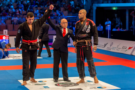 ABU DHABI, UAE - APRIL 19, 2016: ABU DHABI WORLD PROFESSIONAL JIU-JITSU CHAMPIONSHIP 2016 in the IPIC ARENA. Fighters with brown belts. Referee announces the winner. Front view.のeditorial素材