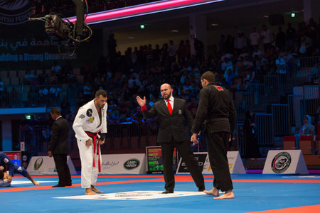ABU DHABI, UAE - APRIL 19, 2016: ABU DHABI WORLD PROFESSIONAL JIU-JITSU CHAMPIONSHIP 2016 in the IPIC ARENA. Fighters with black belts are going to fight. Referee gives them permission.のeditorial素材