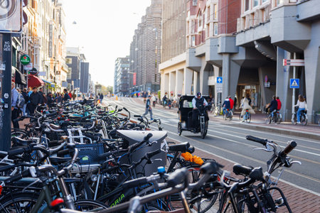 Ordinary Amsterdam street with parked bicycles and cyclists, Netherlands.