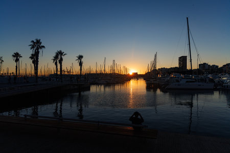 Sunset at the yacht marina in Alicante, Spain. Man on a bench.の写真素材