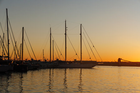 Silhouettes of sailboats and masts in the marina at sunset.の写真素材