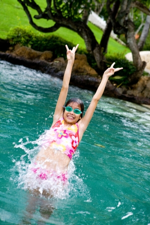 Young girl jumps backward into swimming poolの写真素材