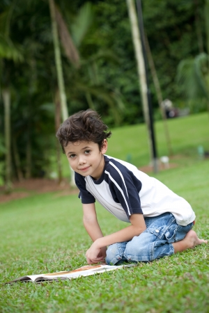Young boy enjoying his reading book in outdoor parkの写真素材