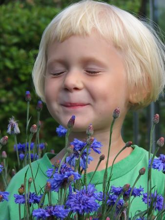 Little blond girl with blue flowers.の写真素材