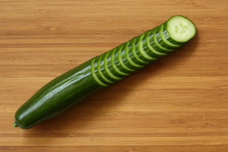 Sliced ripe cucumber on bamboo cutting board.の写真素材