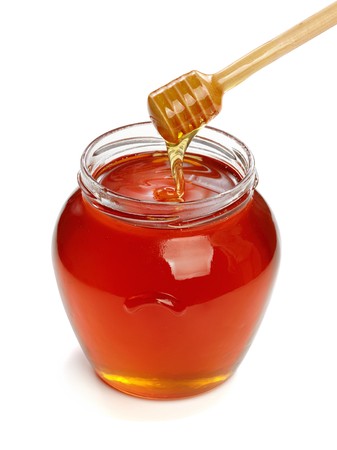 Wooden dipper with jar of honey, isolated on the white backgroundの写真素材