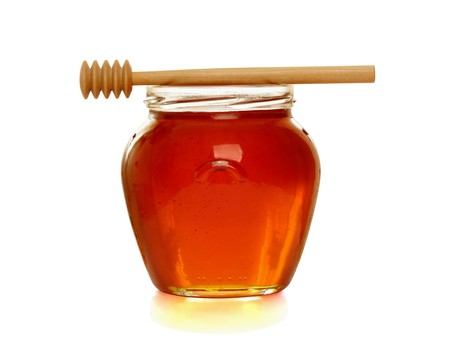 Wooden dipper with jar of honey, isolated on the white backgroundの写真素材