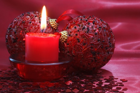 Burning candle and christmas balls on the red background.の写真素材