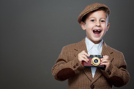 Cute boy with vintage photo camera on the grey background. ( Retro style.)の写真素材