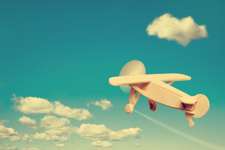 Wooden plane flying in the sky, with space for text.の写真素材