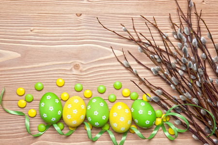 Easter eggs, chocolate candies and willow branches on wooden background.の写真素材