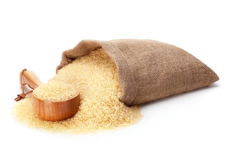 Rice in burlap sack and woodenware, isolated on the white background.の写真素材