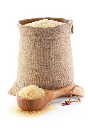 Rice in burlap sack and woodenware, isolated on the white background.の写真素材